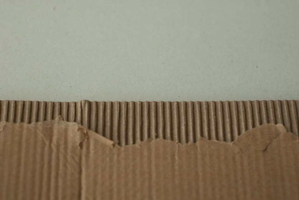 Cardboard with a torn edge against a wall