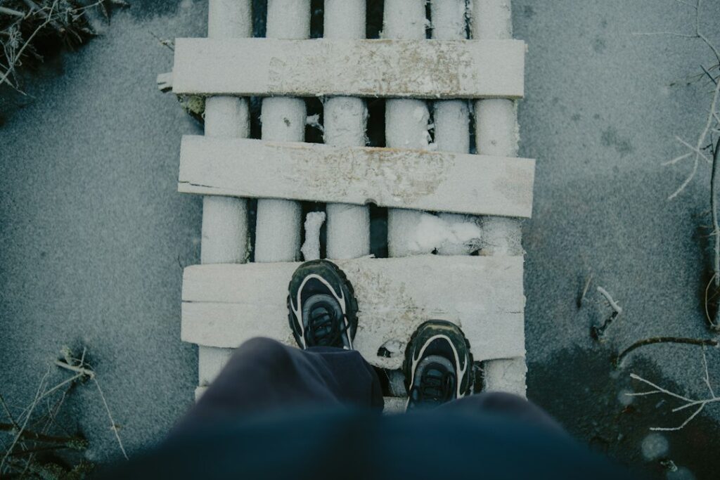 Person standing on a wooden bridge over frozen water