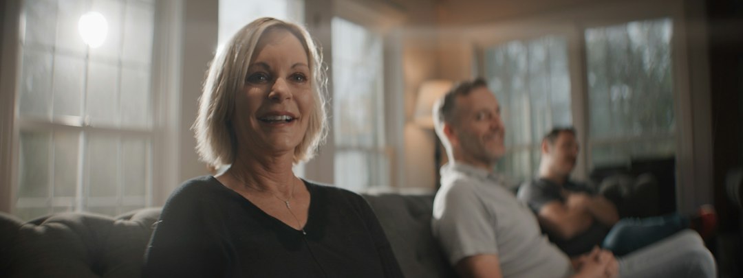 A smiling woman sitting on a couch with others