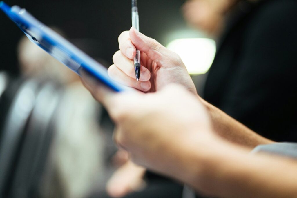 Hand holding pen over a blue clipboard