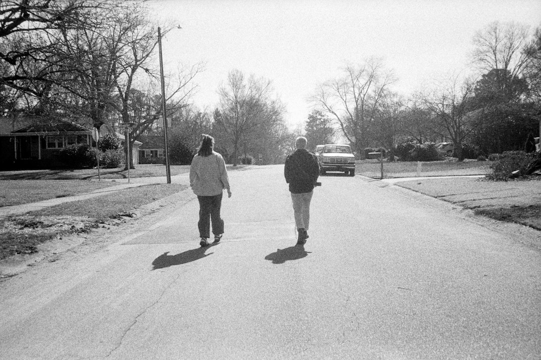 Two people walk down a suburban street